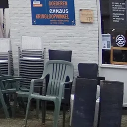 Diverse tuinstoelen en radiators uitgestald buiten tegen een witte muur