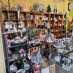 Winkelvloer met houten stellingen vol decoratieve huishoudartikelen, serviesgoed en woonaccessoires