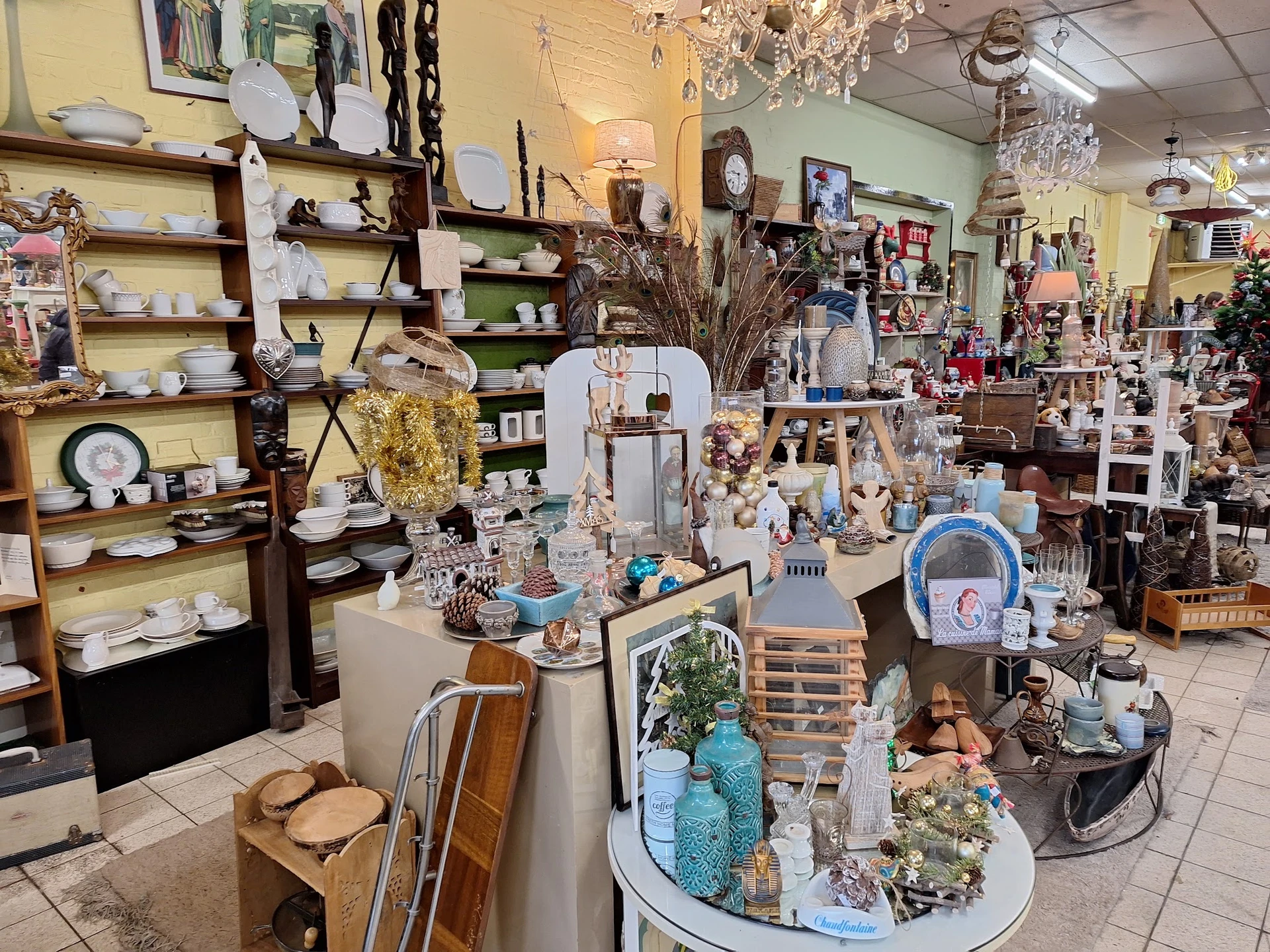 Winkelvloer met uitgestalde decoraties, servies, vazen en diverse huishoudelijke spullen op tafels en in stellingen