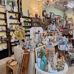 Winkelvloer met uitgestalde decoraties, servies, vazen en diverse huishoudelijke spullen op tafels en in stellingen