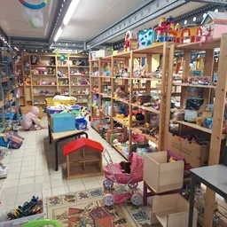 Overzicht van speelgoedafdeling met houten stellingen vol speelgoed, poppen en kinderspeelgoed in kringloopwinkel