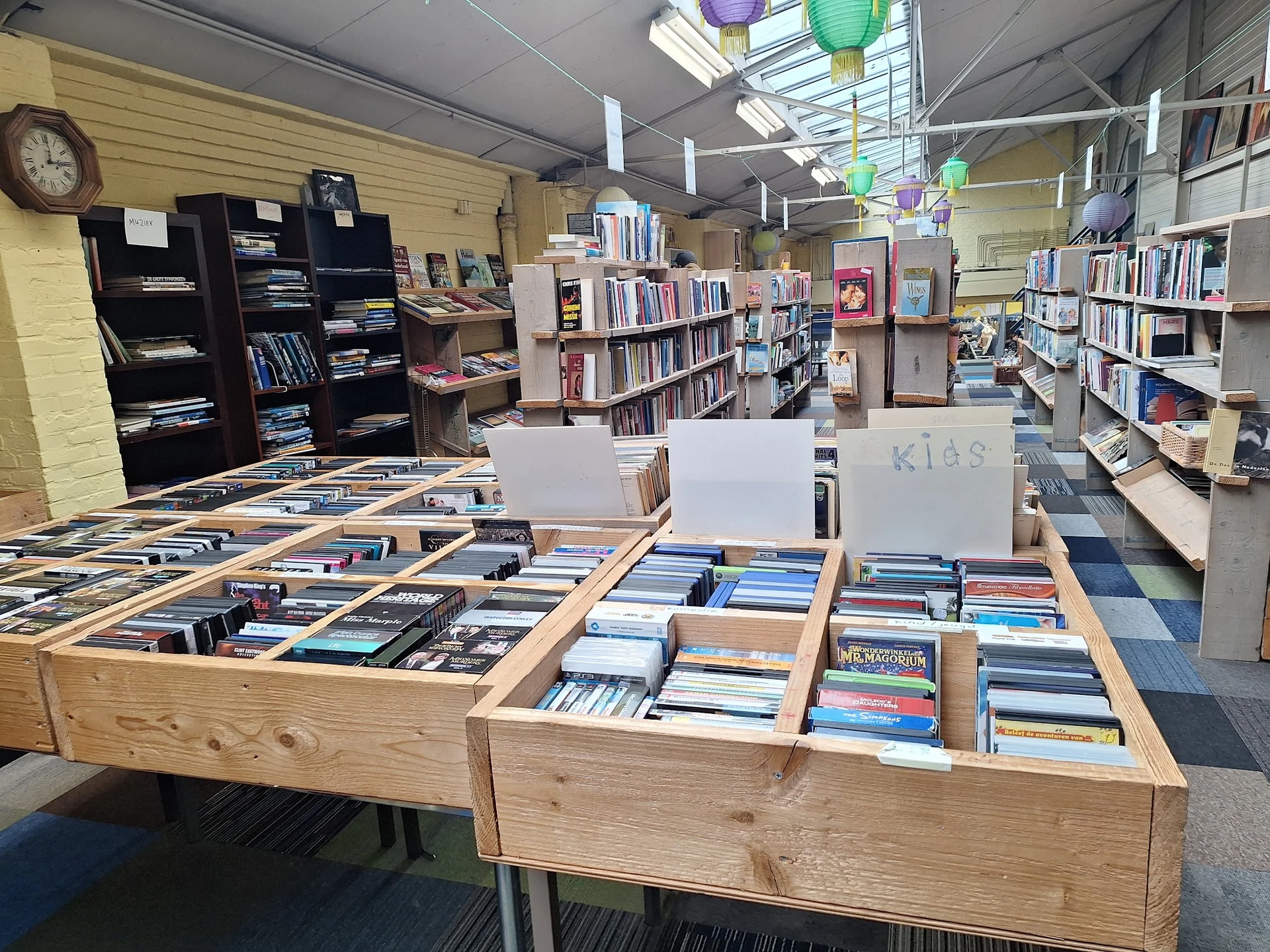 Houten display-tafels met uitgestalde cd's en dvd's in een kringloopwinkel