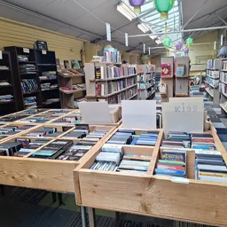 Houten display-tafels met uitgestalde cd's en dvd's in een kringloopwinkel