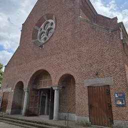 Bakstenen kerkgevel met groot rond raam en twee bogen met houten deuren