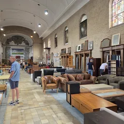 Ruim interieur van kringloopwinkel met meubels, kasten en diverse tweedehands spullen