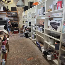 Winkelvloer met witte stellingen vol diverse tweedehands artikelen en spullen