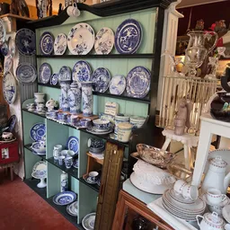 Groene vitrinekast vol blauw-wit porselein servies, borden en decoratieve items