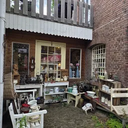 Uitgestalde tweedehands artikelen in een kringloopwinkel, waaronder servies, decoratieve voorwerpen en huishoudelijke spullen