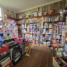Winkelvloer met houten planken en uitgebreide stellingen vol dozen, boeken en speelgoed tegen de wanden