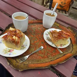 Tafel met twee koppen koffie en twee borden met gebak op een terras