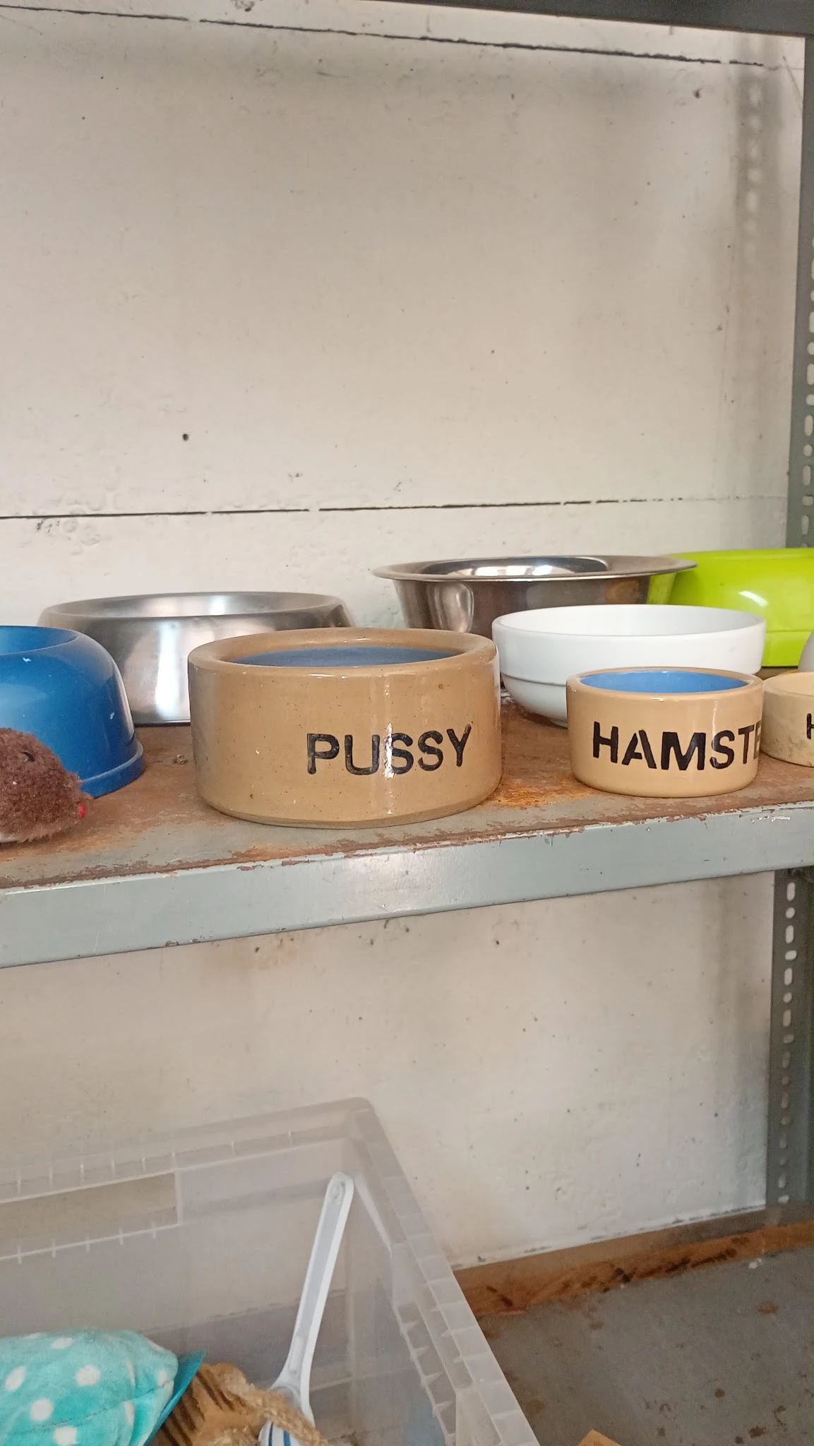 Voerbakken voor huisdieren met opschriften 'PUSSY' en 'HAMST' op een plank