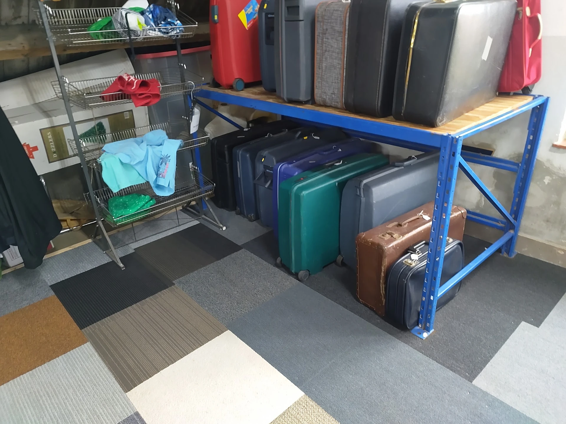 Blauwe stellage met uitgestalde koffers en tassen in verschillende kleuren en maten
