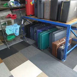 Blauwe stellage met uitgestalde koffers en tassen in verschillende kleuren en maten