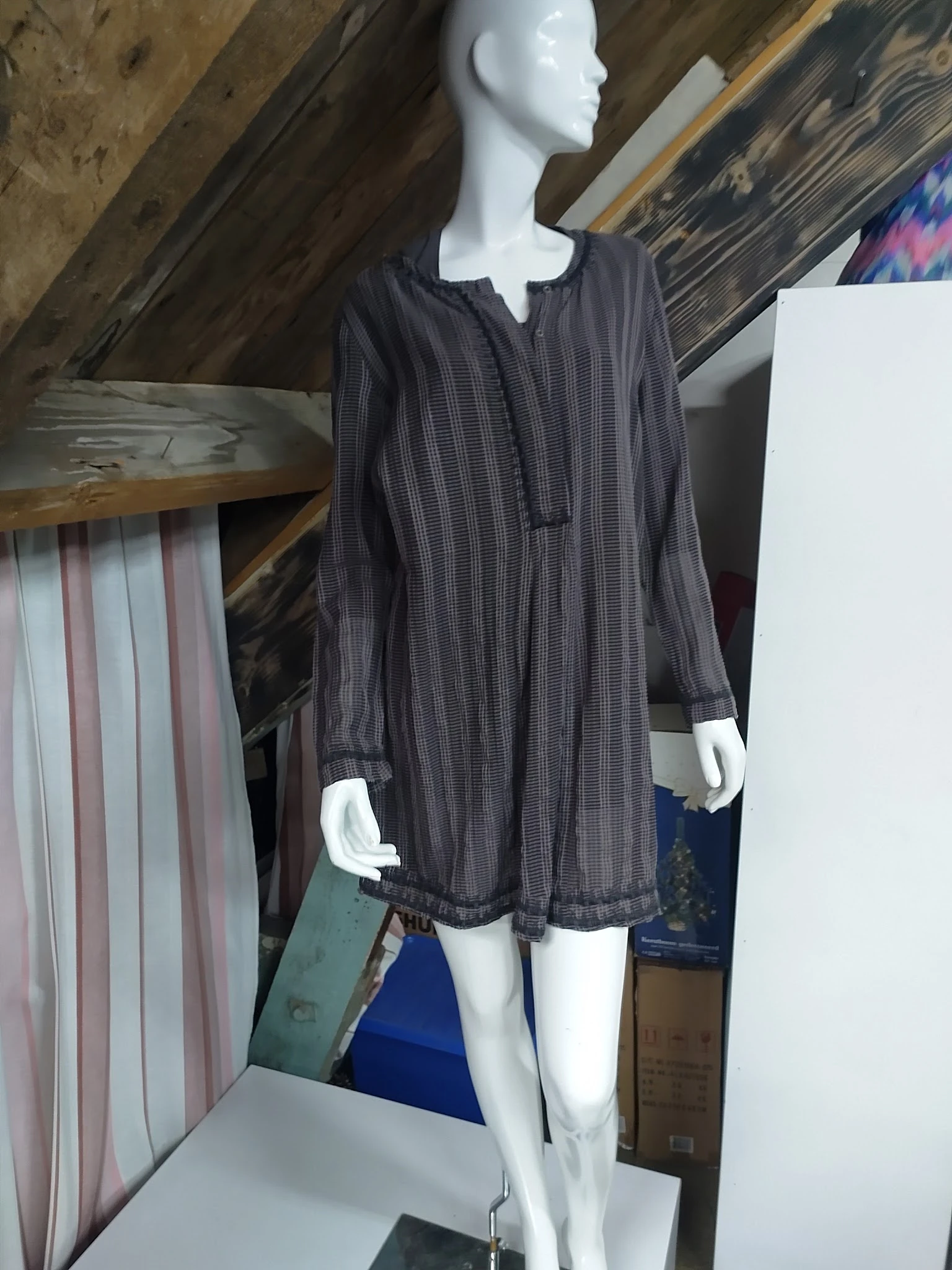 Mannequin draagt donkergrijs geruit hemdachtig kledingstuk met lange mouwen