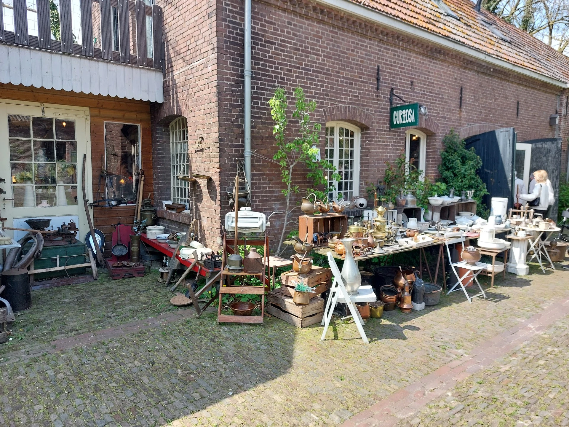 Uitgestalde tweedehands spullen en meubels buiten op het terrein van de kringloopwinkel