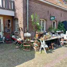 Uitgestalde tweedehands spullen en meubels buiten op het terrein van de kringloopwinkel