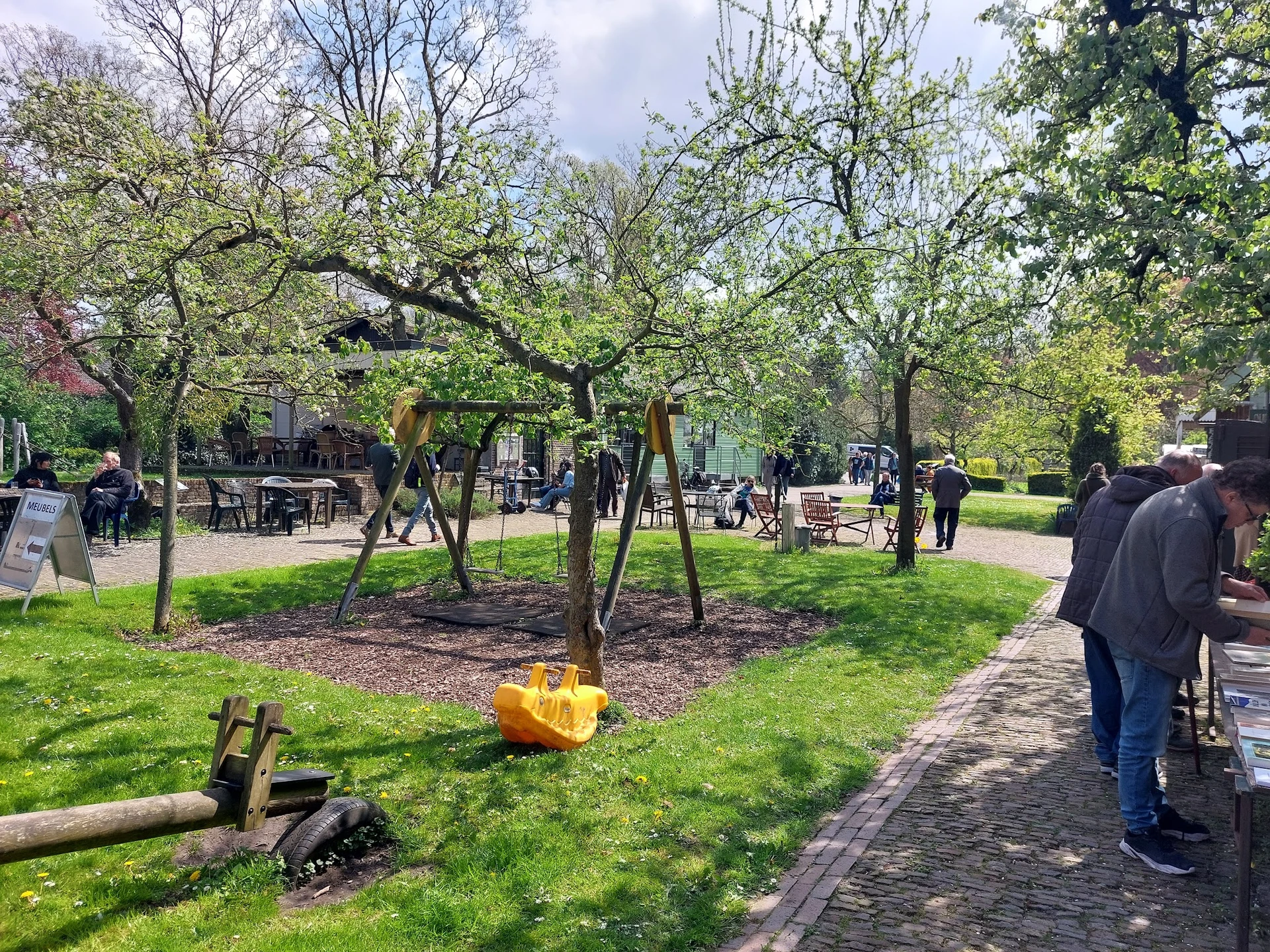 Groen park met bomen, wandelpaden en bezoekers op een zonnige dag