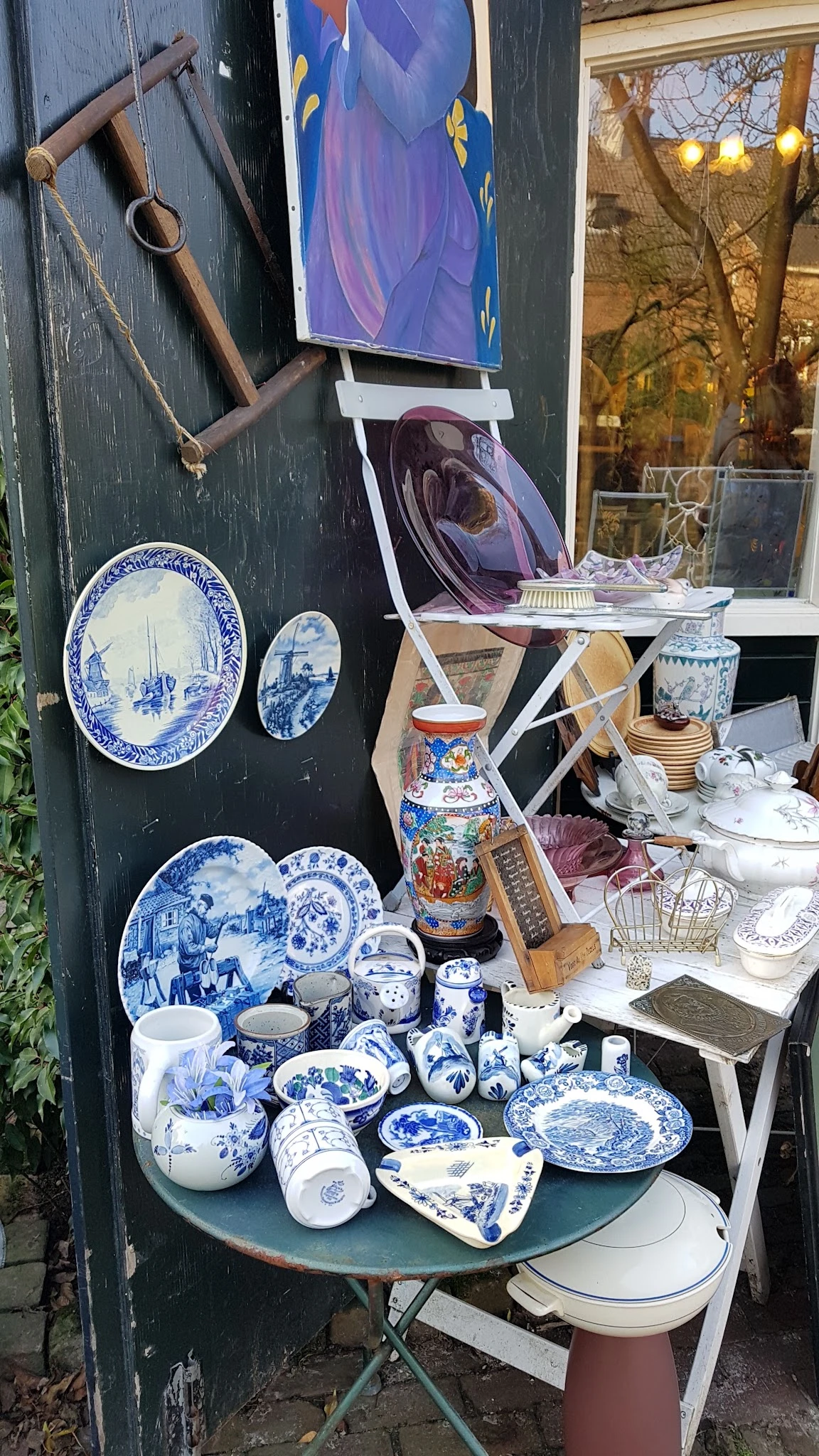 Uitgestalde serviesgoed en decoratieve artikelen: blauwe borden, vazen, potten en huishoudelijke spullen