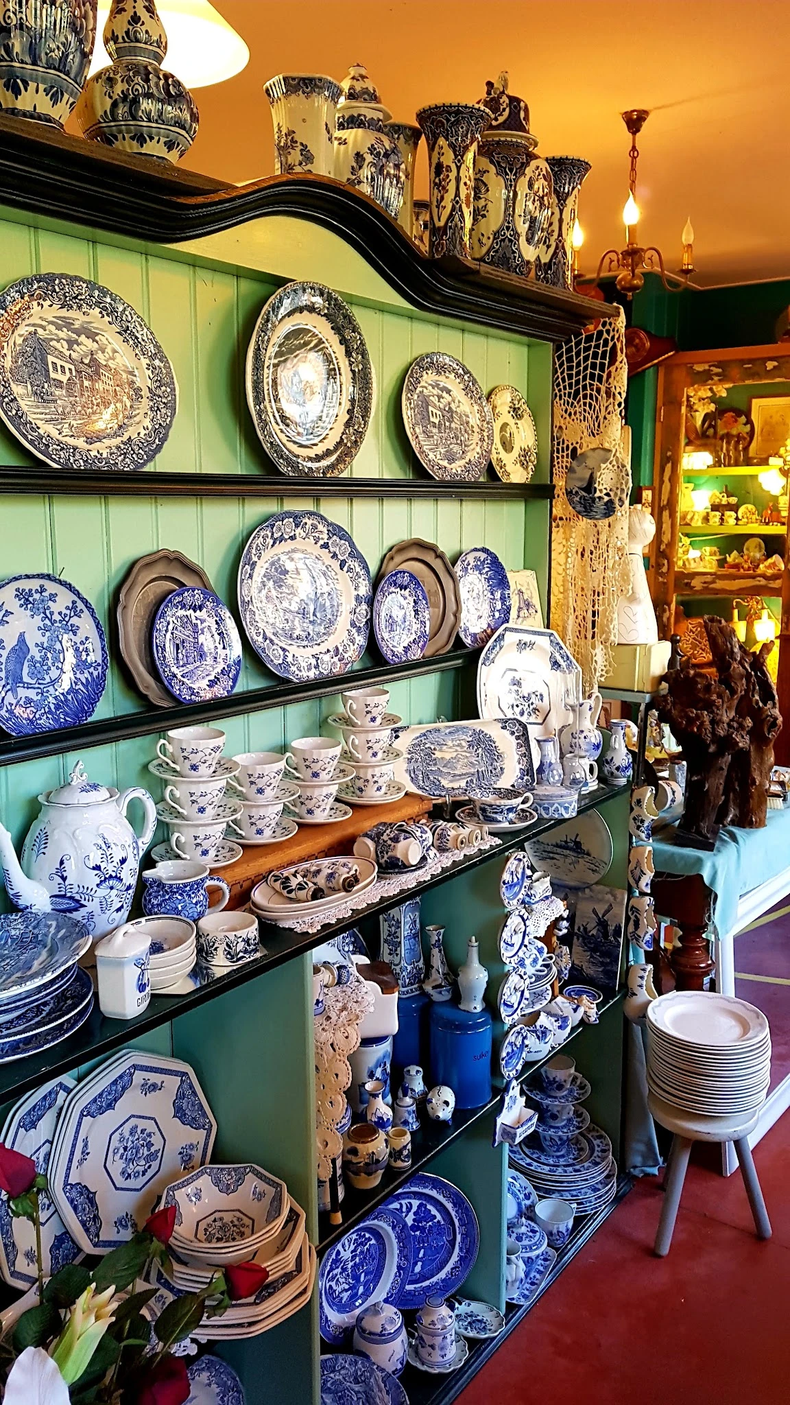 Uitgestalde blauwe en witte porseleinen borden, kopjes en servies in een kringloopwinkel