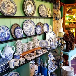 Uitgestalde blauwe en witte porseleinen borden, kopjes en servies in een kringloopwinkel