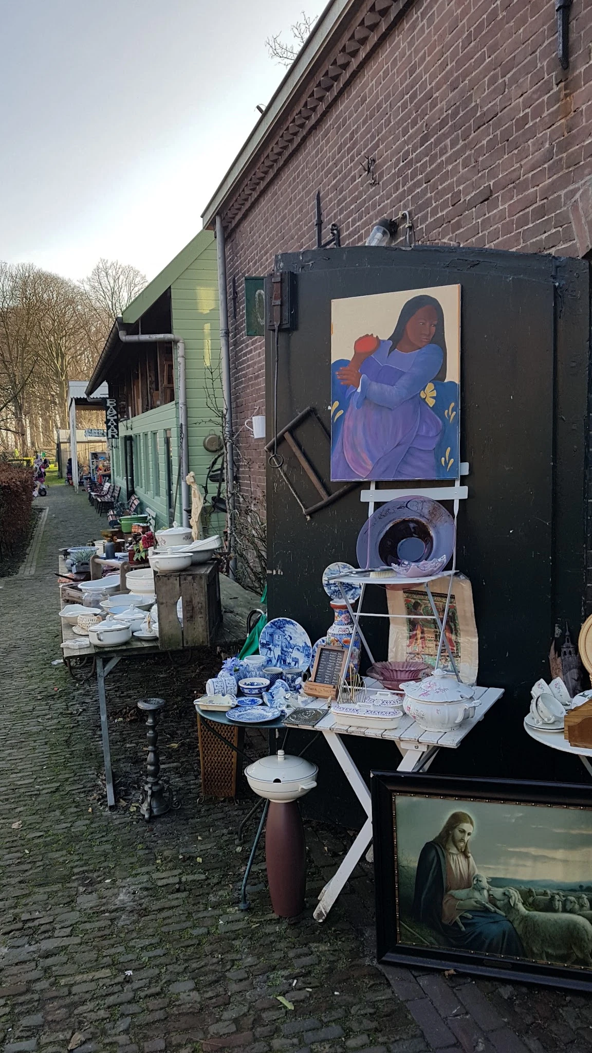 Uitgestalde tweedehands servies, borden en decoratieve items buiten een kringloopwinkel