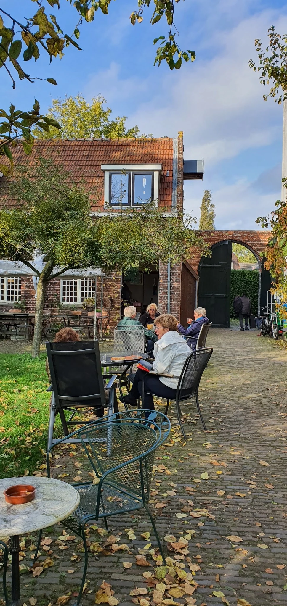 Bezoekers zitten buiten op het terras van de kringloopwinkel met stoelen rond een tafel
