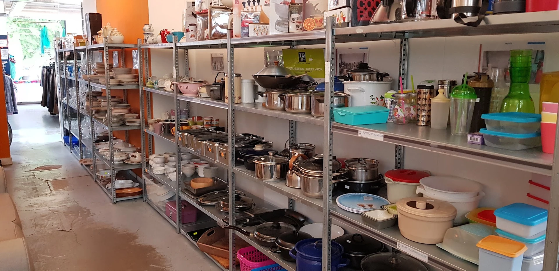 Metalen stellingen met kookgerei, pannen, potten en keukenaccessoires in verschillende maten en kleuren