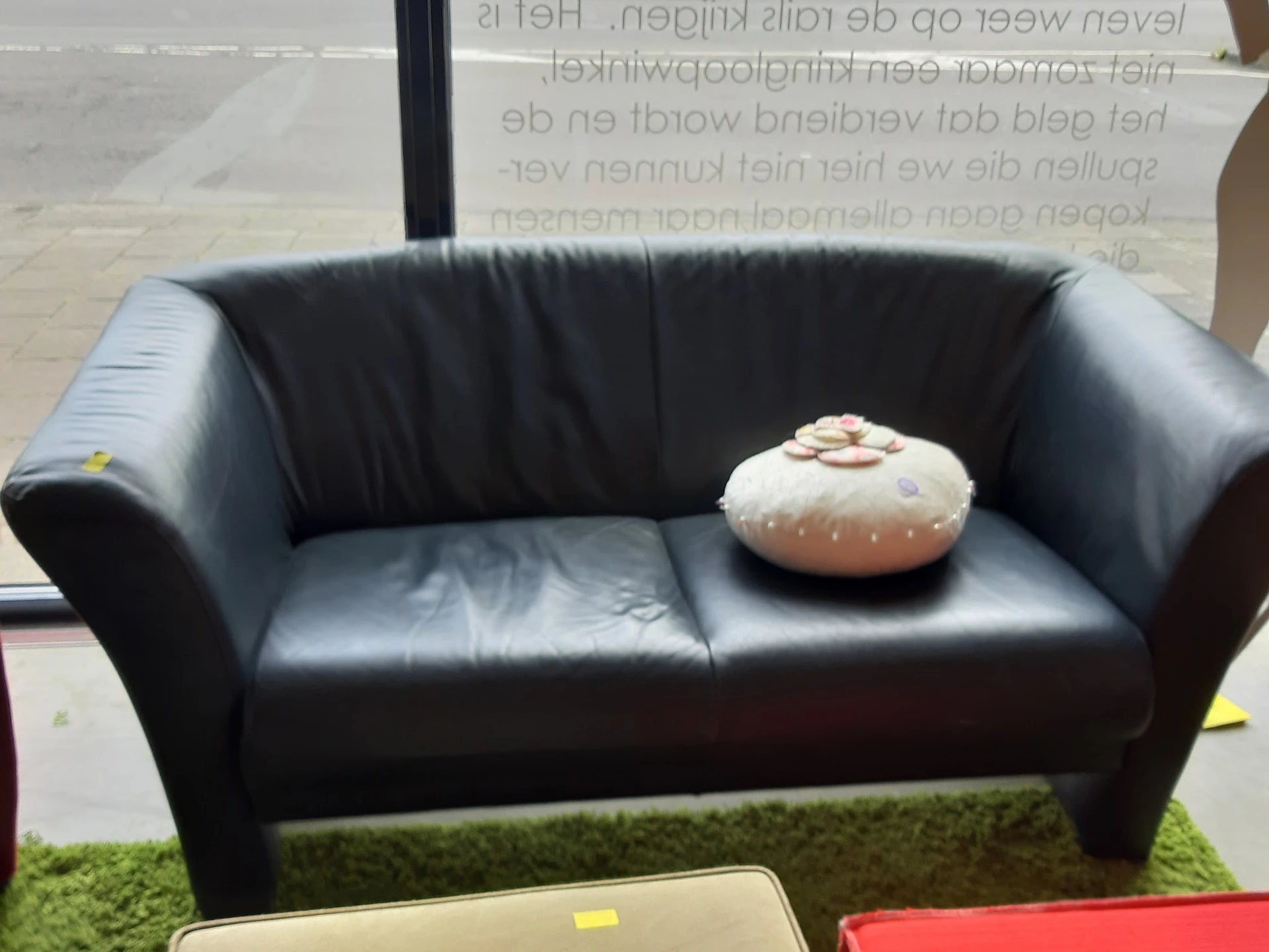 Zwarte leren tweezitsbank met decoratieve donut-vormige kussen erop