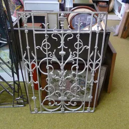 Decoratief ornamentaal hek of poort met wit metalen sierwerk, staande in de winkel