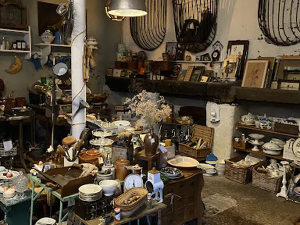 Overzicht van winkelinterieur met tafels vol servies, vazen, decoratieve artikelen en houten meubels