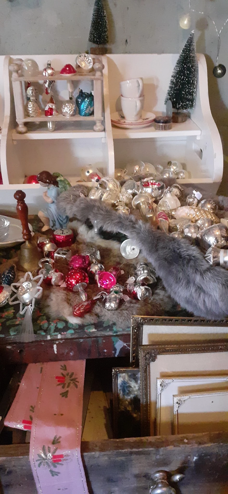 Kerstversiering en glazen ornamenten op tafel met poes die ernaar snuffelt