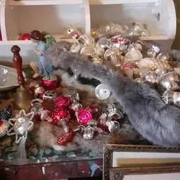 Kerstversiering en glazen ornamenten op tafel met poes die ernaar snuffelt