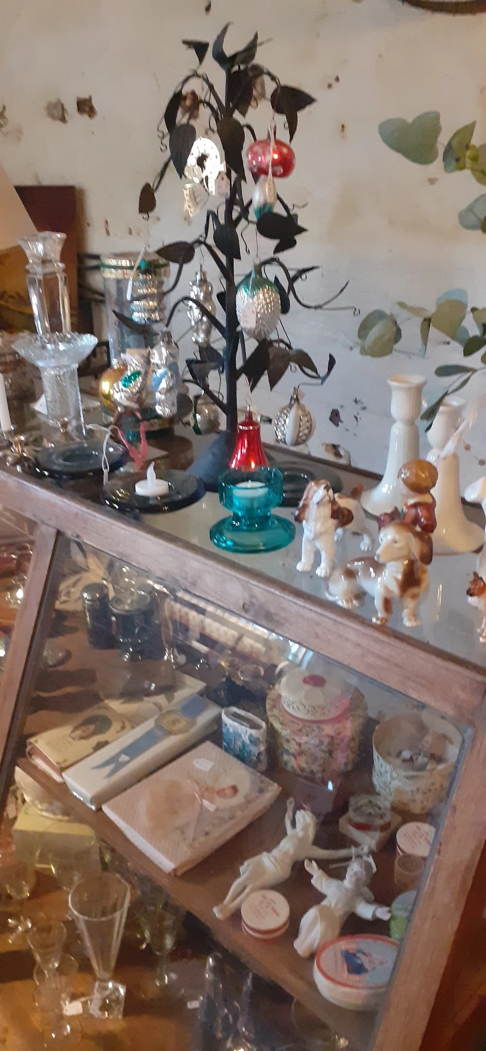Vitrinekast met diverse decoratieve items zoals kandelaars, beeldjes en kunstobjecten