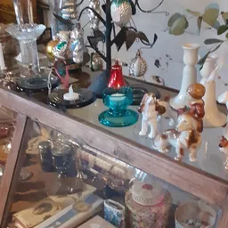 Vitrinekast met diverse decoratieve items zoals kandelaars, beeldjes en kunstobjecten
