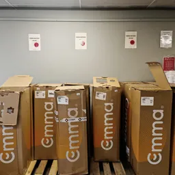 Rij met bruine Cimmo-dozen gestapeld in een opslagruimte, waarschijnlijk nieuwe voorraad voor de winkel
