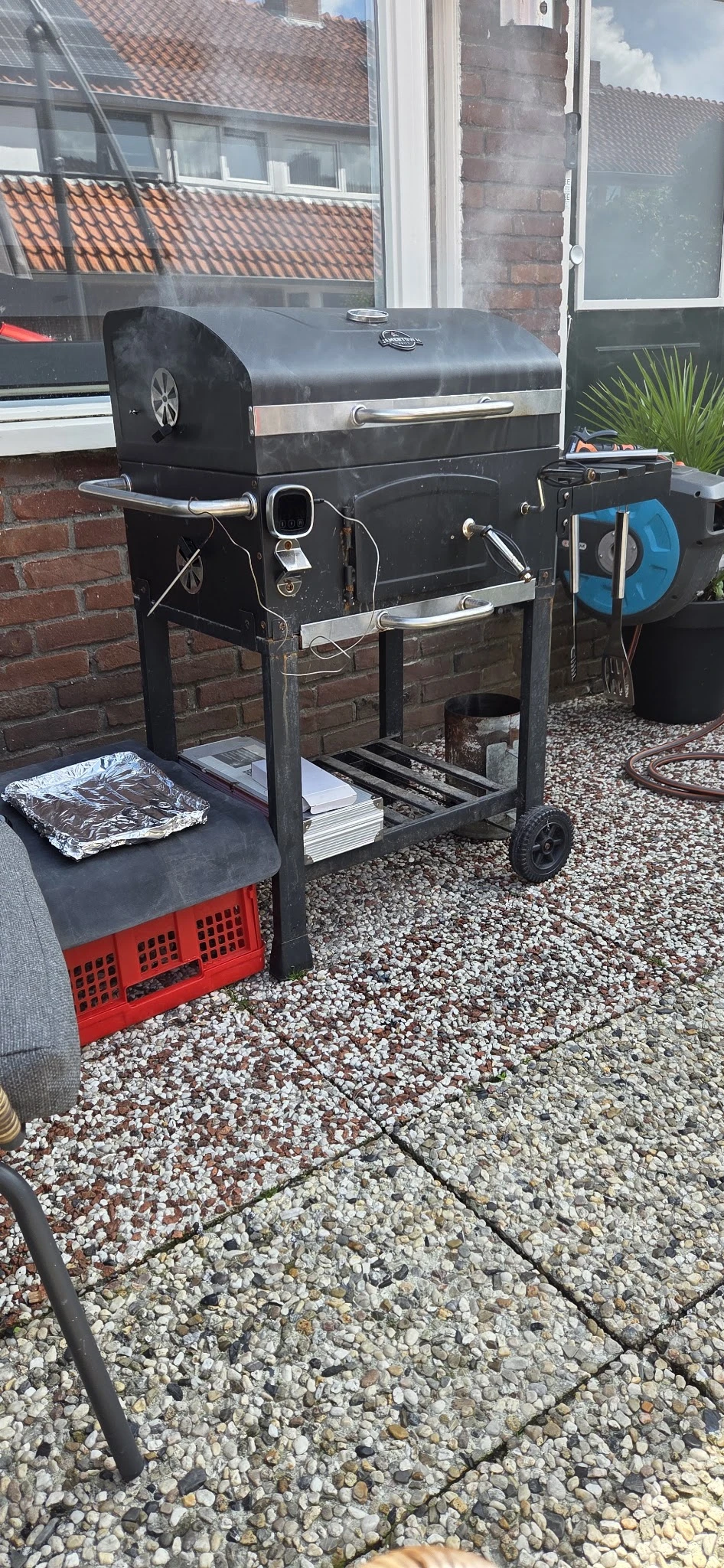 Tweedehandsartielen op een karretje buiten: serviesgoed, stapels papier en een rode plastic krat