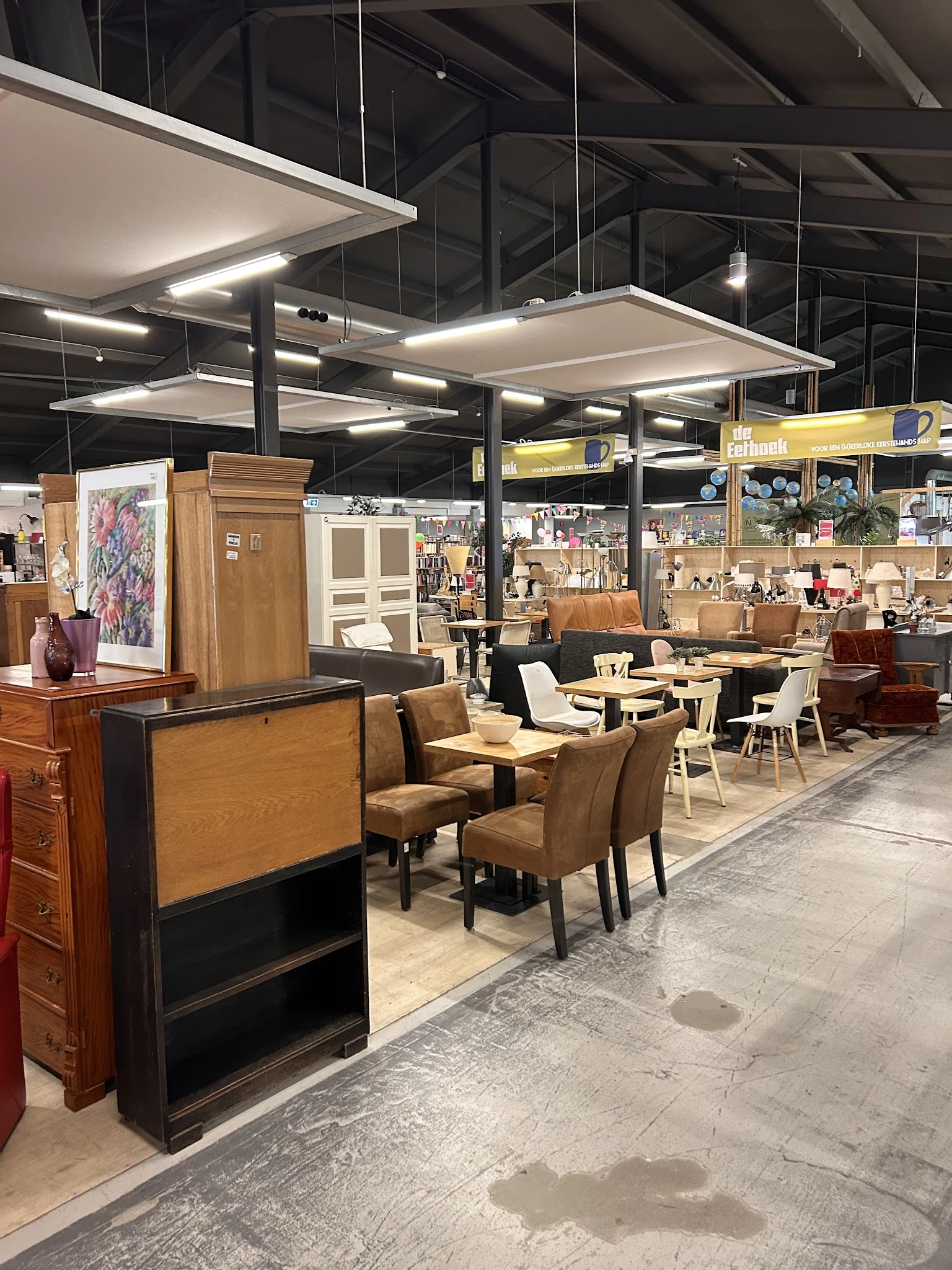 Winkelvloer met bruine stoelen, tafels en meubels in een kringloopwinkel