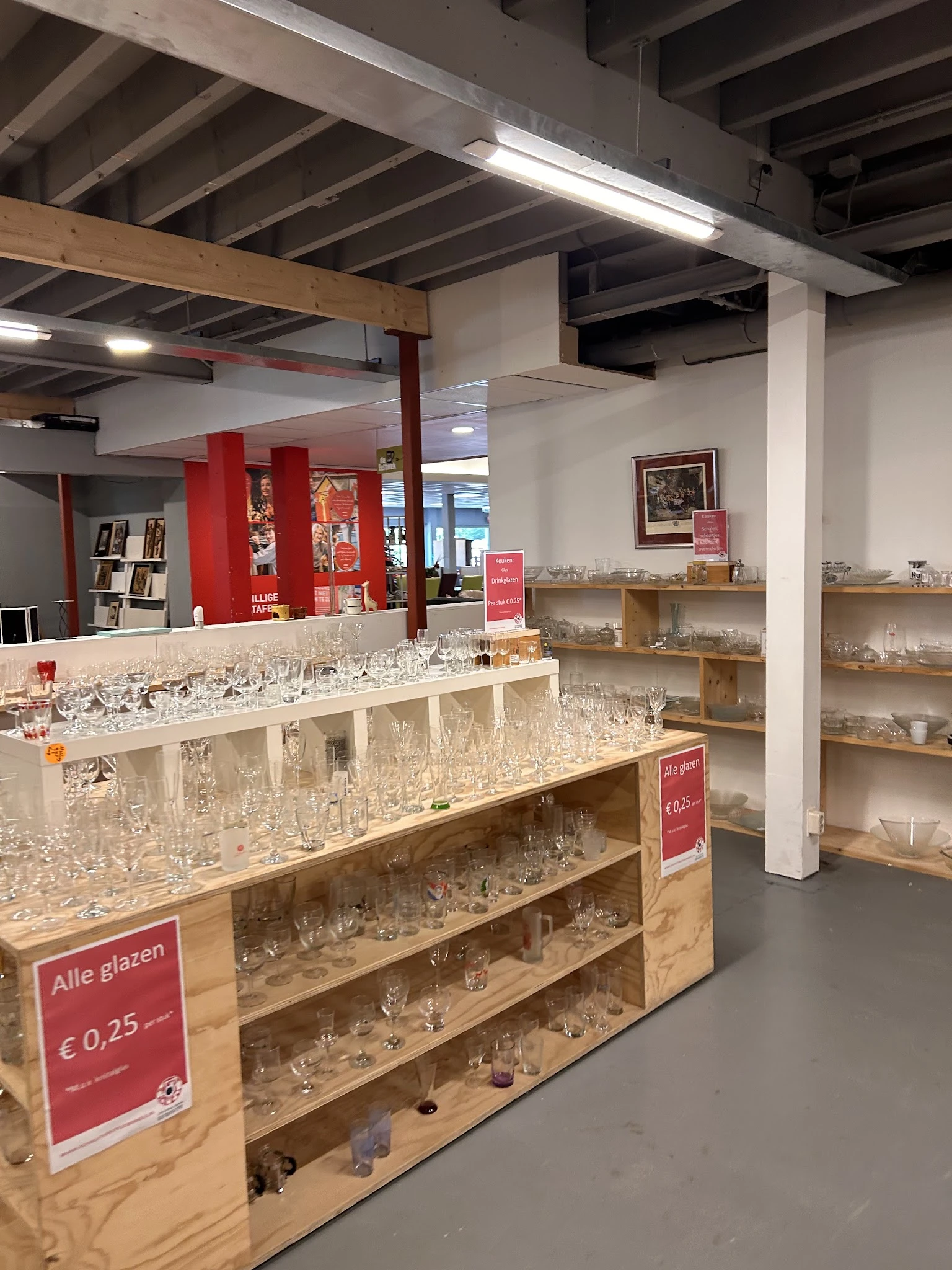 Uitgestalde glazen en kristal op houten planken en toonbank in de winkel