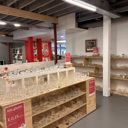 Uitgestalde glazen en kristal op houten planken en toonbank in de winkel