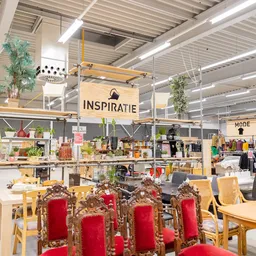 Ruim winkelinterieur met stellingen, kledingrekken, decoratie en een inspiratiehoek met rood-gouden kerstdecoratie