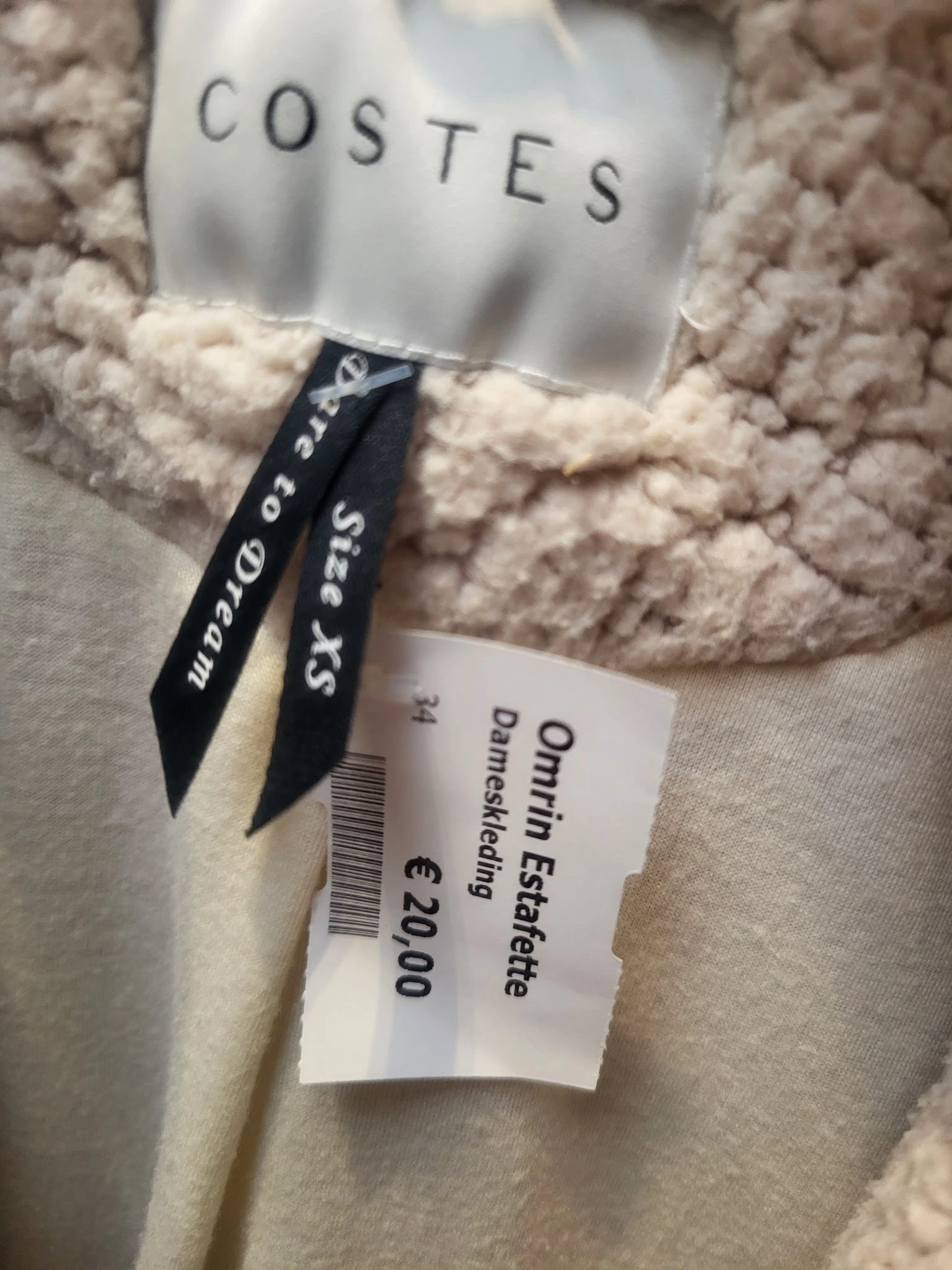 Tweedehands beige gebreide trui met zwart etiket en prijskaartje