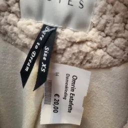 Tweedehands beige gebreide trui met zwart etiket en prijskaartje