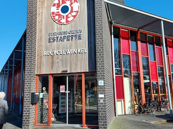 Voorgevel van recyclewinkel met bakstenen muur, rode ramen en ingang met rode kozijnen