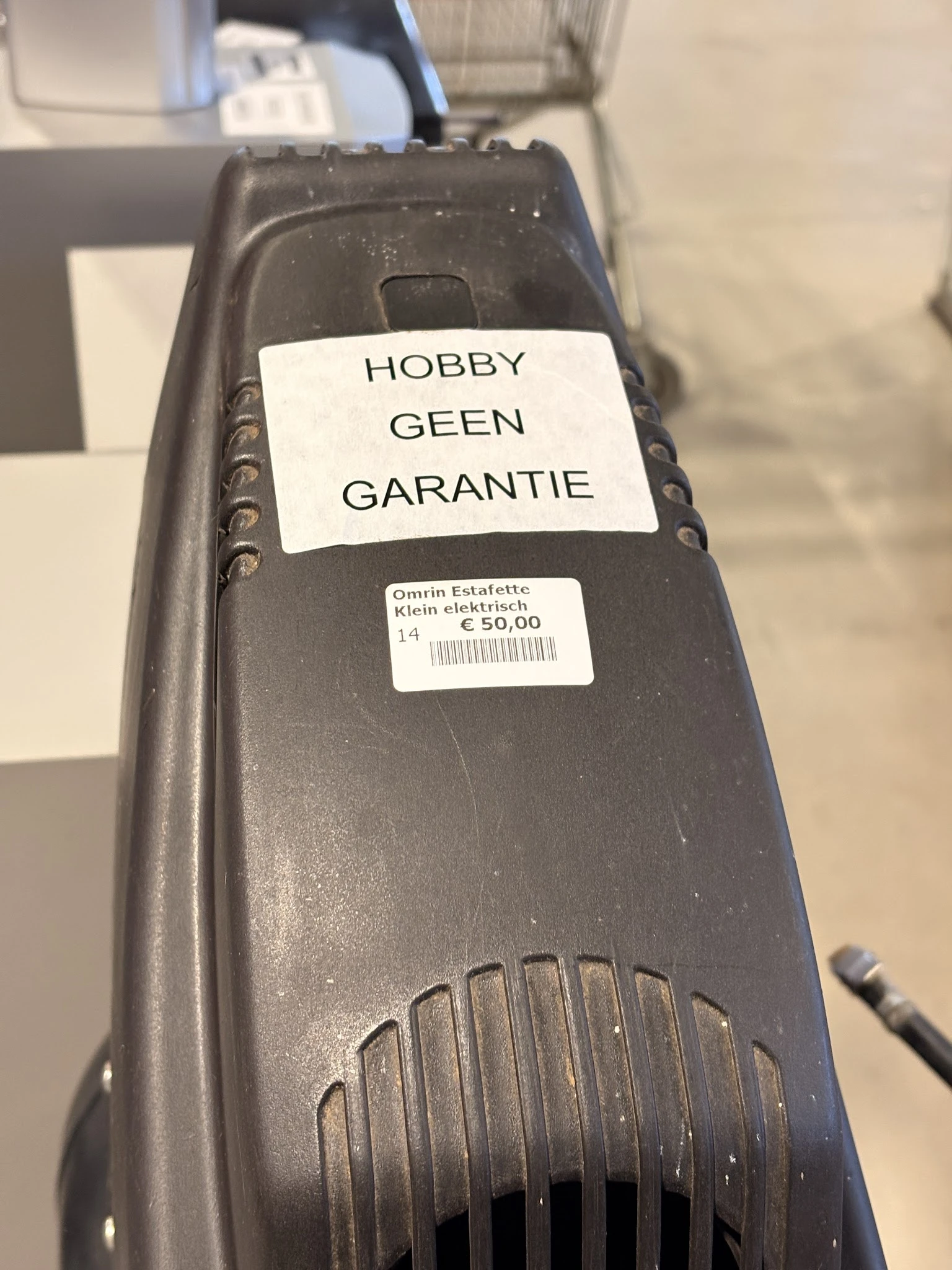 Close-up van een zwart elektronisch apparaat met labels 'HOBBY GEEN GARANTIE' en een prijssticker.