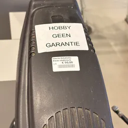 Close-up van een zwart elektronisch apparaat met labels 'HOBBY GEEN GARANTIE' en een prijssticker.