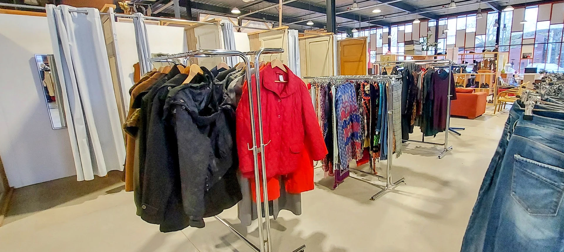 Rekken met tweedehands kleding, waaronder jassen en jasjes in verschillende kleuren en stoffen