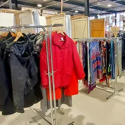 Rekken met tweedehands kleding, waaronder jassen en jasjes in verschillende kleuren en stoffen