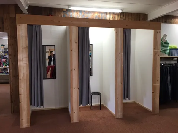 Houten paskamers met grijze gordijnen in een kringloopwinkel