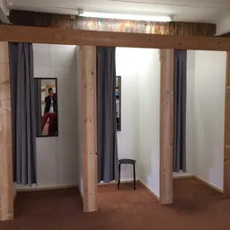Houten paskamers met grijze gordijnen in een kringloopwinkel