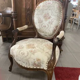 Antieke fauteuil met houten carving en crèmekleurig brocaatbekleding met bloemmotief